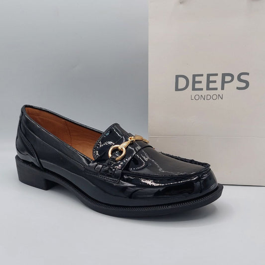 Side profile of women's black patent loafer with a gold T-bar, showcasing its sleek silhouette and sophisticated design, perfect for London fashion.