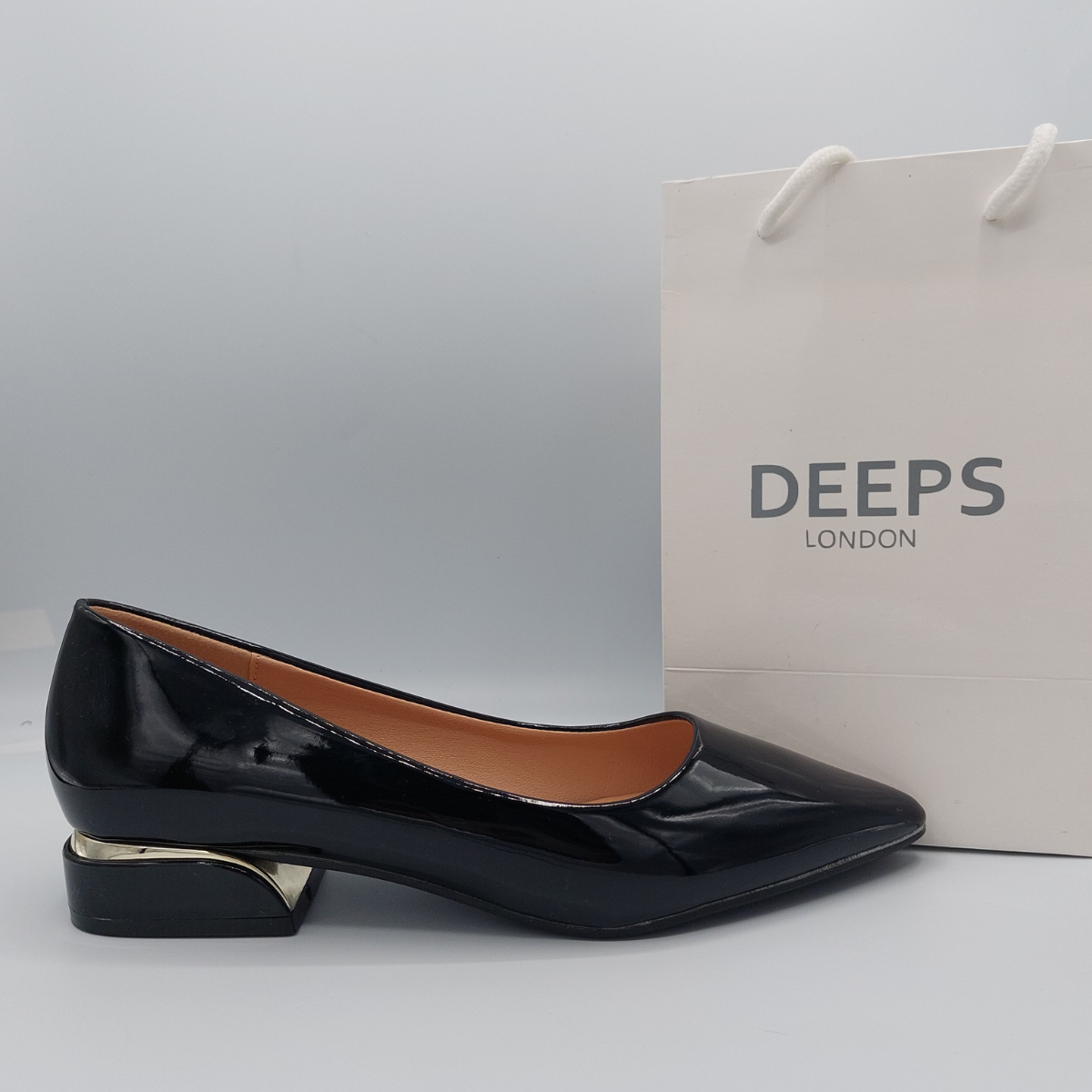 Side view of women's black patent classic slip-on flat shoes with a low heel, a timeless style in London.