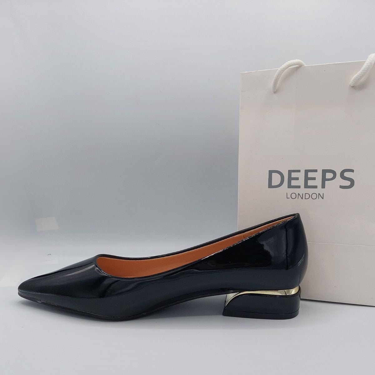 Side profile of sleek black patent slip-on flat shoes for women, showcasing the low heel and elegant silhouette, perfect for London fashion.