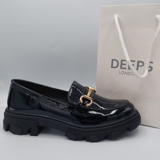Side view of women's black patent T-bar flat loafer with a chunky platform sole, a bold and edgy shoe in London.