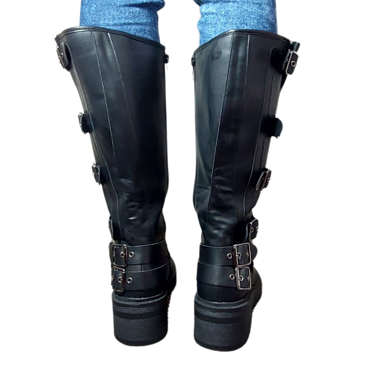 Woman's leg wearing stylish black buckle detail mid-calf faux leather boots with a side zip, a confident footwear choice for London life.