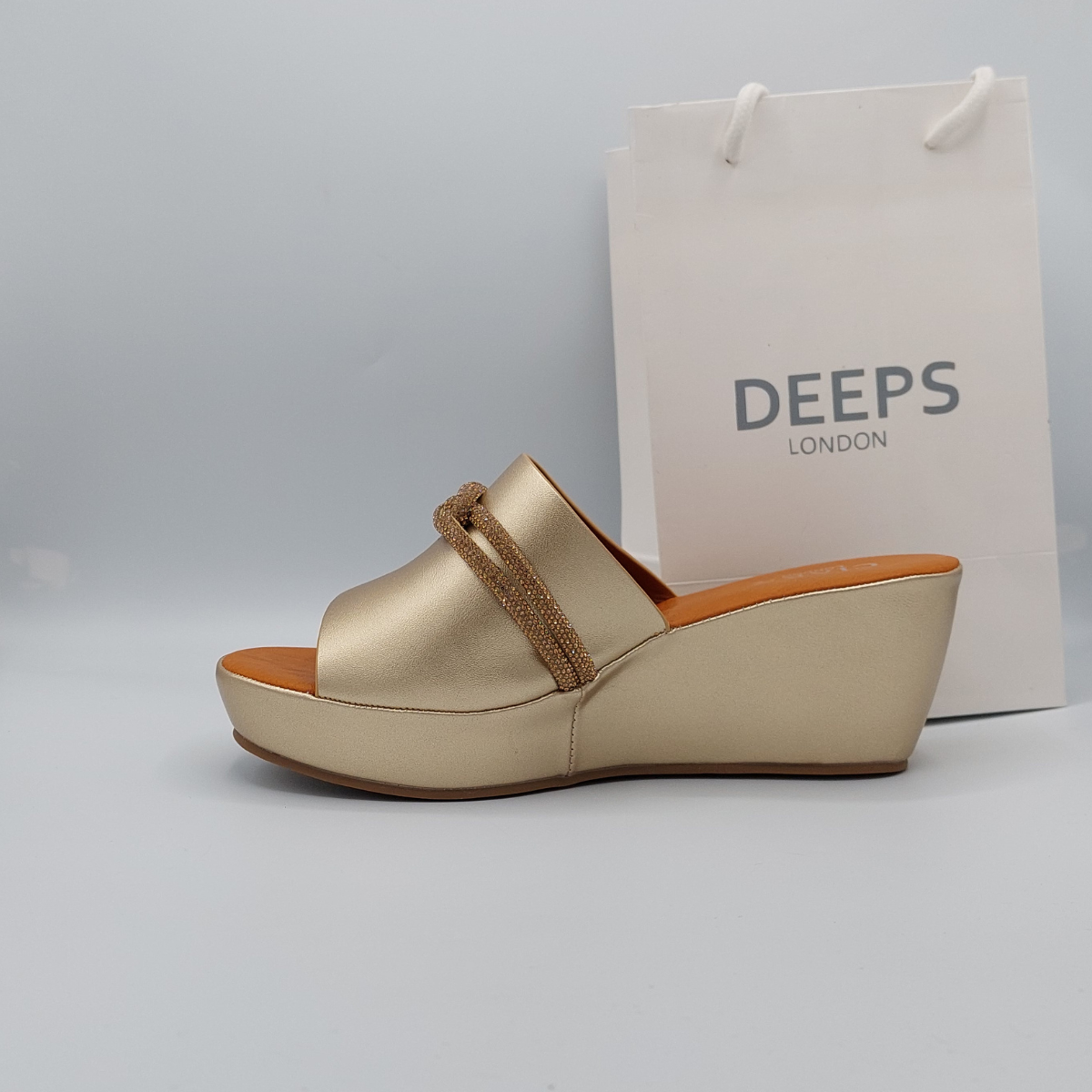 Woman's foot wearing stylish Carey open toe diamante wedge platform mule slider sandal in gold, a fashionable and glamorous choice for London summer events from DeepsLondon.