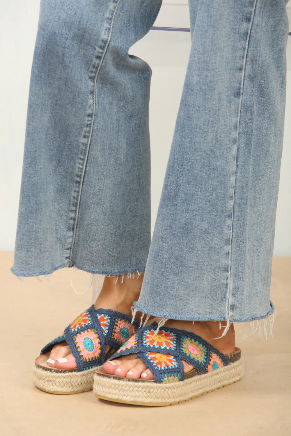 Woman's foot wearing stylish crochet detail cross strap printed sandals in navy, a fashionable and comfortable choice for holiday adventures.