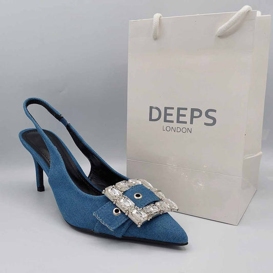 Side profile of women's blue denim pointed toe slingback heels, showcasing the heel and diamante buckle detail for London fashion.