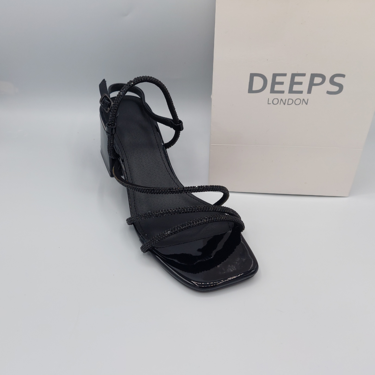Woman's foot wearing stylish diamante embellished block heel sandals, a comfortable and fashionable choice for London life.