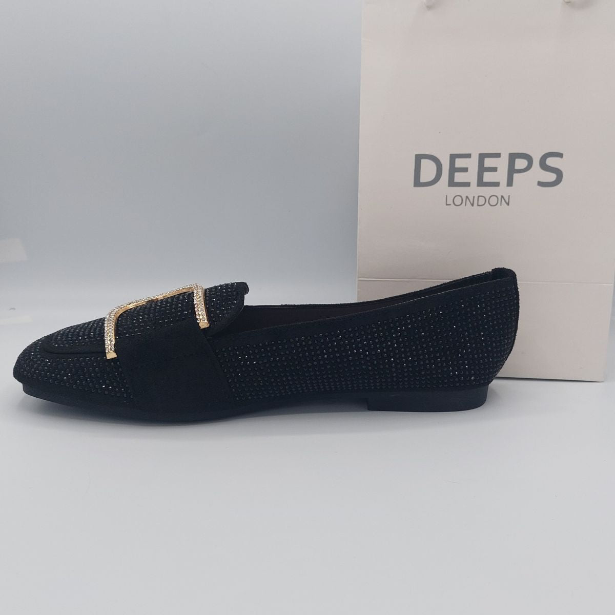 Close-up of the diamante glitter and gold metal decor on women's black loafers, highlighting their elegant design in London.