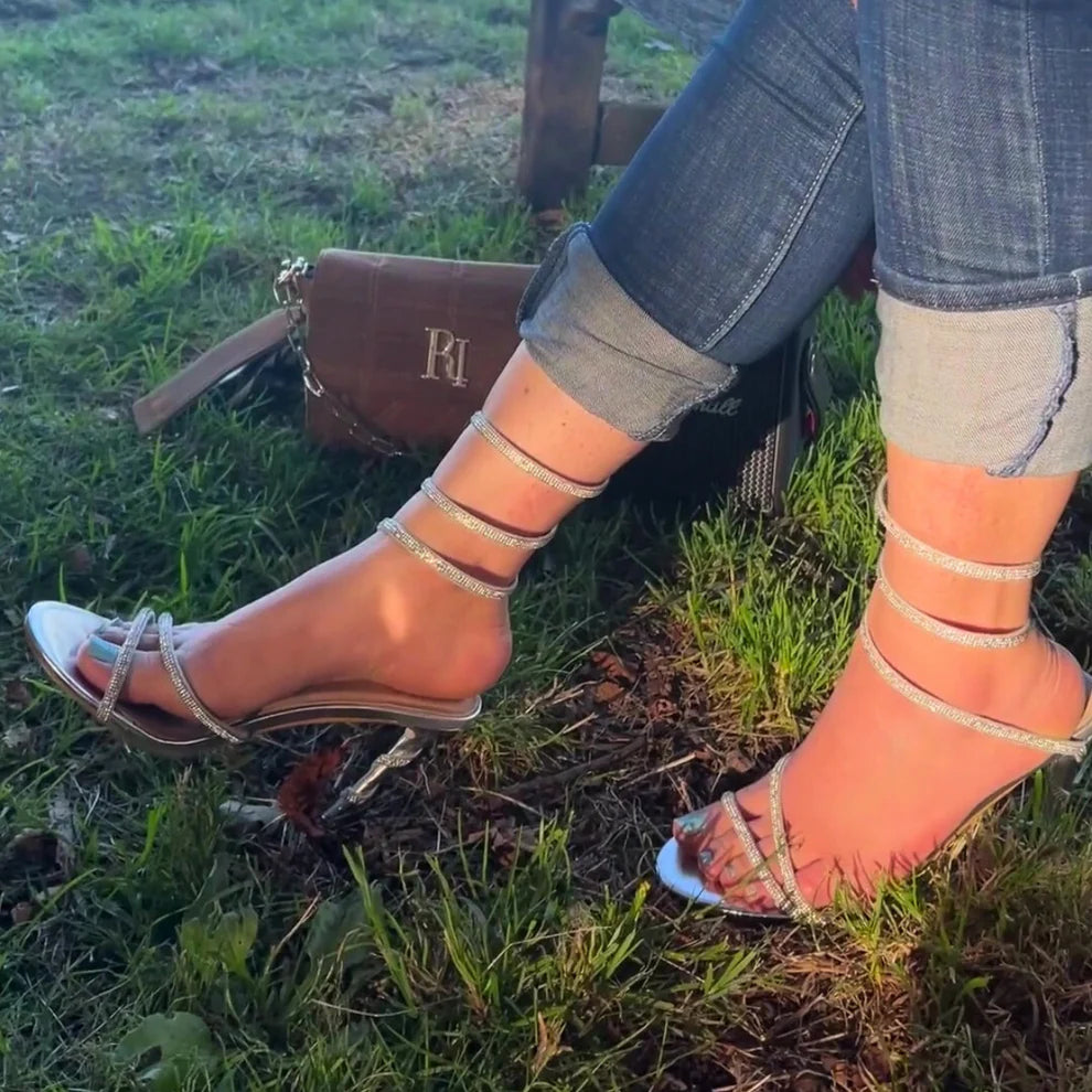 Woman's foot wearing stylish diamante spiral wrap around stiletto heels in silver, a comfortable and fashionable choice for London occasions from DeepsLondon. The spiral wrap is elegantly displayed.