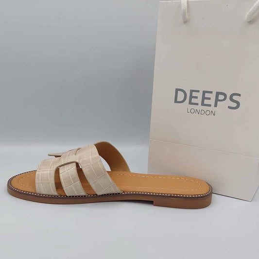 Side profile of women's beige faux leather slip-on sliders featuring the cut-out strap detail, showcasing their easy-to-wear style for London life.