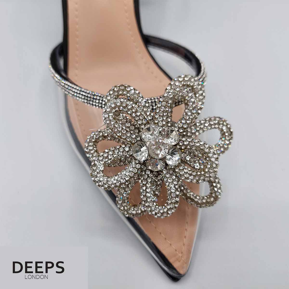 Close-up of the floral embellishments, perspex accents, and ankle tie on women's slingback court heels in black satin, highlighting their elegant features suitable for London events.