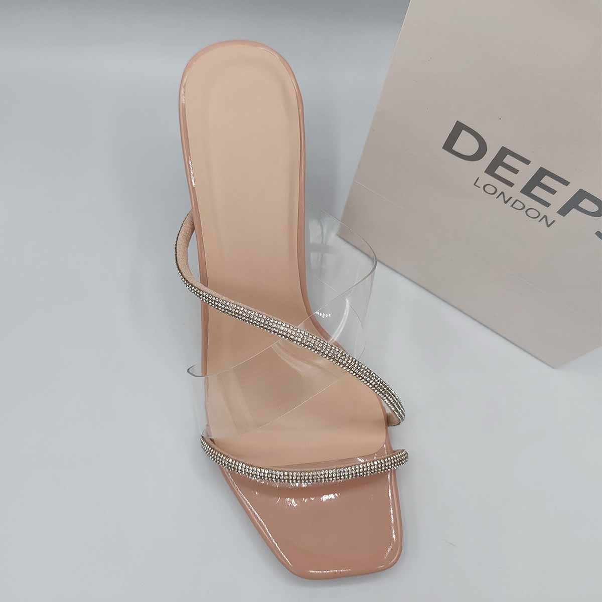 Close-up of the diamante embellishments on the straps of Izza clear perspex block heel mules in beige, highlighting their elegant features for London events.