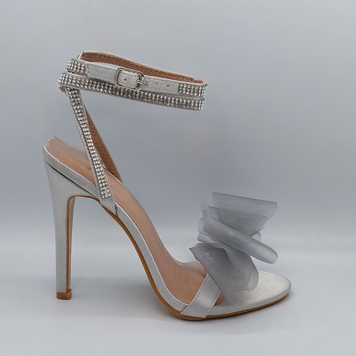 Side profile of Majesty organza bow high heel sandals in silver satin, highlighting the stylish high heel and graceful design, London style from DeepsLondon.