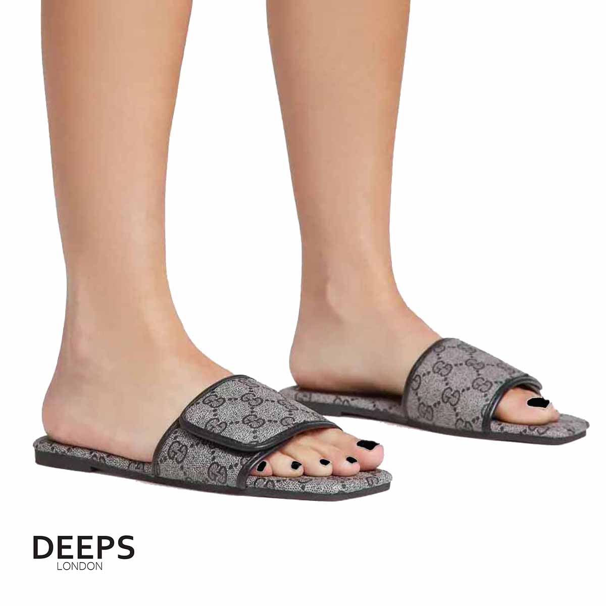 Woman's foot wearing stylish open toe flat slider sandals with a black print, a versatile footwear choice for London life.