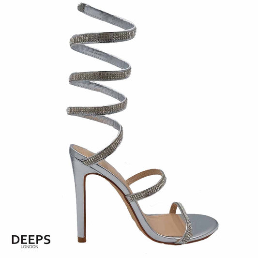 Woman's foot wearing stylish diamante spiral wrap around stiletto heels in silver, a comfortable and fashionable choice for London occasions from DeepsLondon. The spiral wrap is elegantly displayed.
