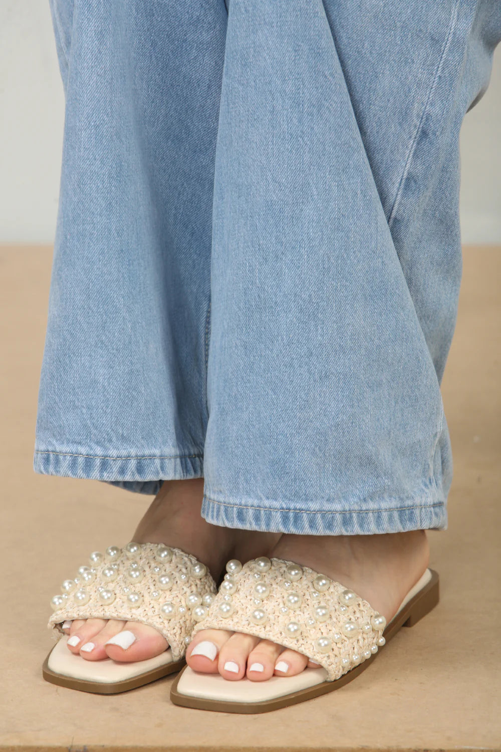 Front view of pearl embellished flat sandals in cream, showcasing the elegant pearl details and comfortable flat sole, London style from DeepsLondon.