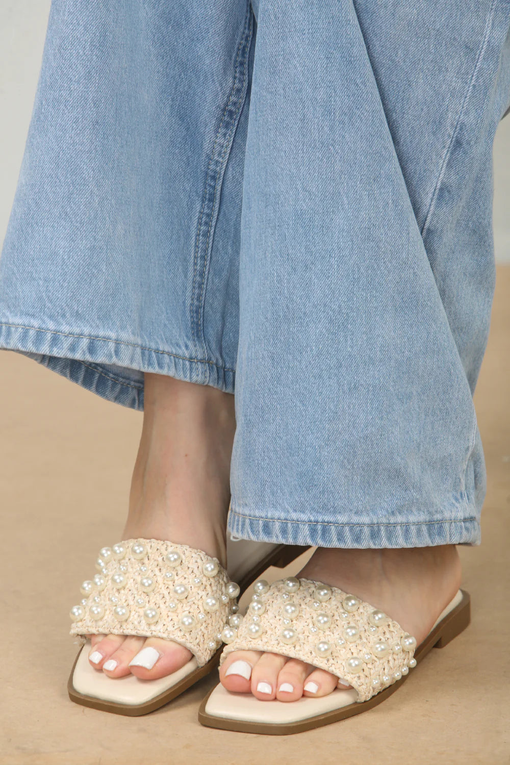 Side profile of pearl embellished flat sandals in cream, highlighting the sleek silhouette and comfortable design, ideal for London strolls.