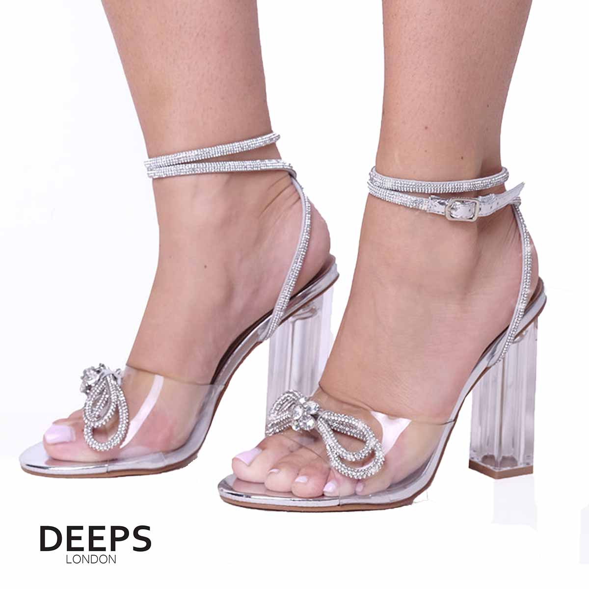 Woman's foot wearing stylish perspex block heel sandal with diamante bow and ankle tie in silver, a comfortable and fashionable choice from DeepsLondon.