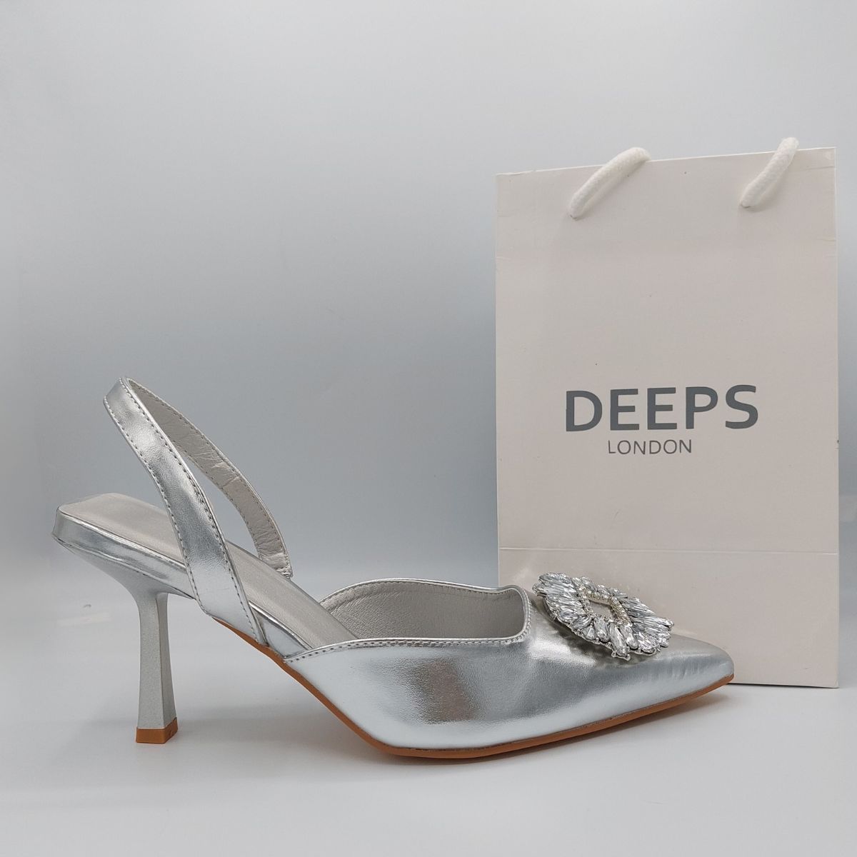Side profile of women's perspex court shoe with diamante brooch detail in Silver PU, showcasing the perspex material and brooch detailing.