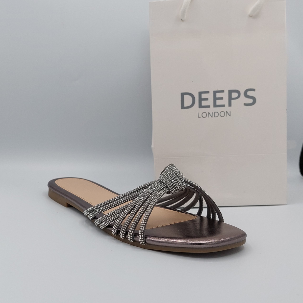 Woman's foot wearing chic black perspex flat slider sandals with diamante detail, a versatile London footwear option.