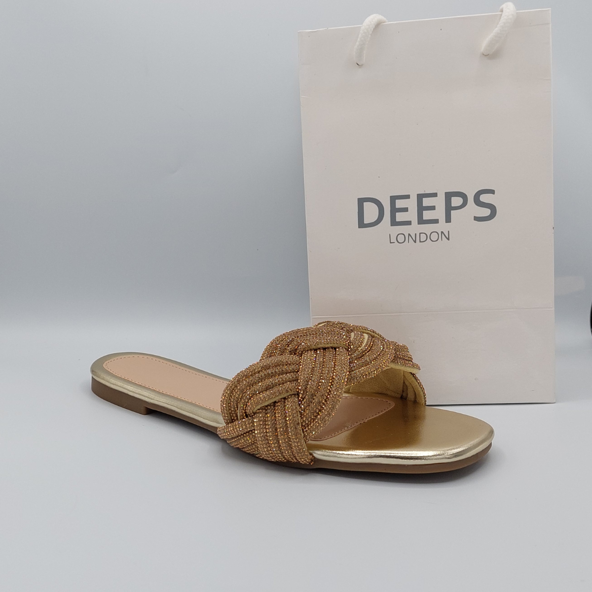 Close-up detail of the sparkling diamante embellishments on the gold perspex slider sandals for women.