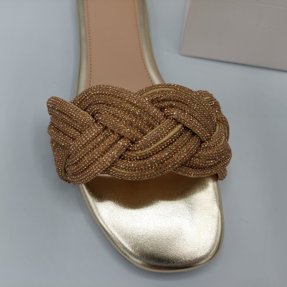 Woman's foot wearing stylish gold perspex flat slider sandals with diamante detail.