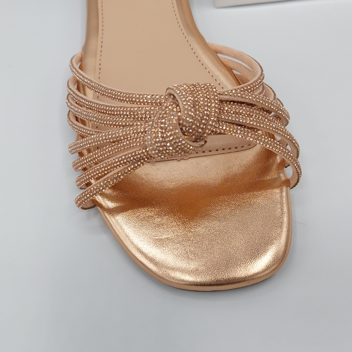 Close-up detail of the shimmering diamante embellishments on the rose gold perspex slider sandals for women, adding a touch of London glamour.