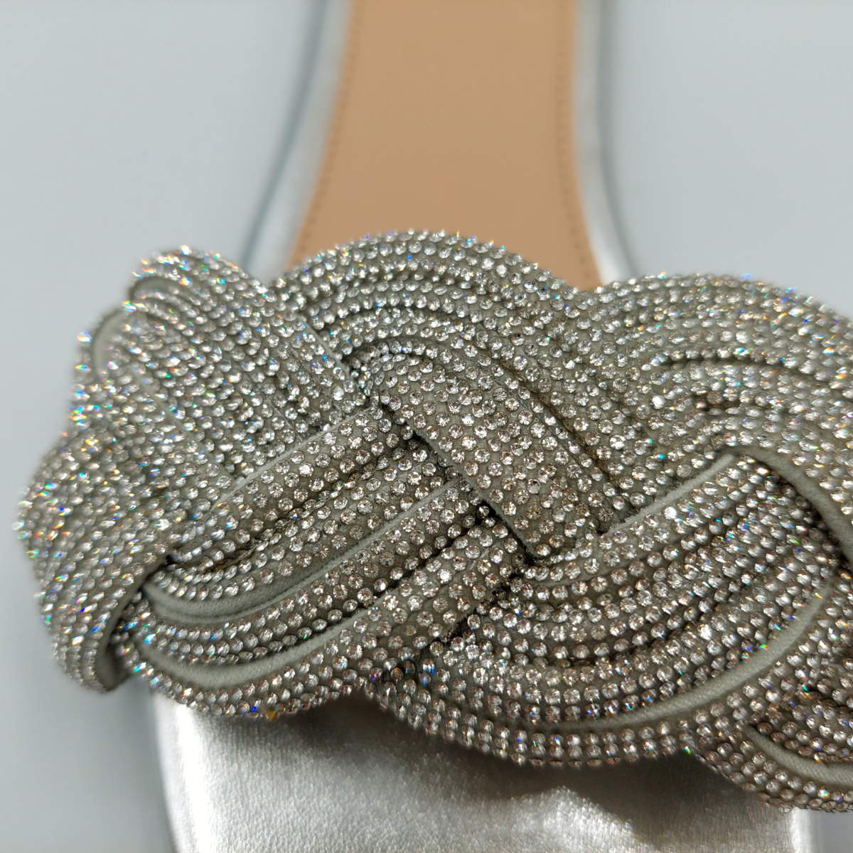 Close-up detail of the shimmering diamante embellishments on the silver perspex slider sandals for women.