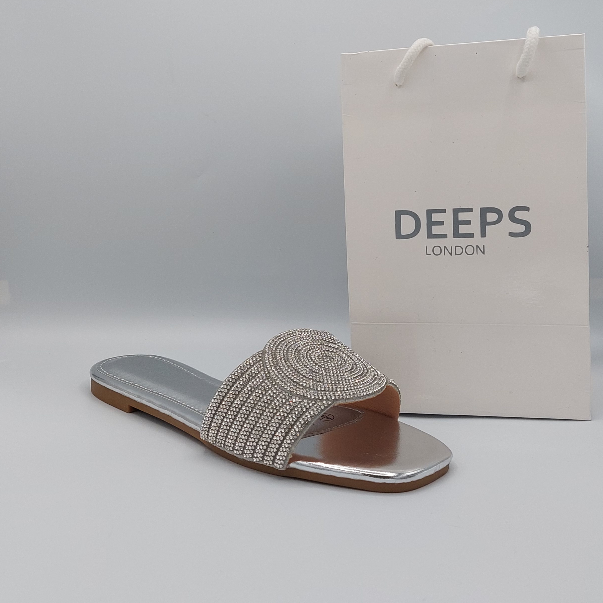 Side profile of silver perspex flat slider sandals for women highlighting the delicate diamante embellishments, a sophisticated London look.