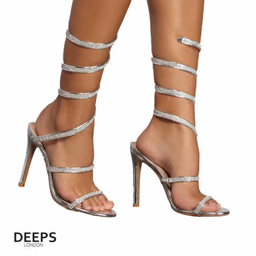 Close-up of the diamante embellishments and spiral wrap strap on stiletto heels in silver, highlighting their elegant and unique design for London events.