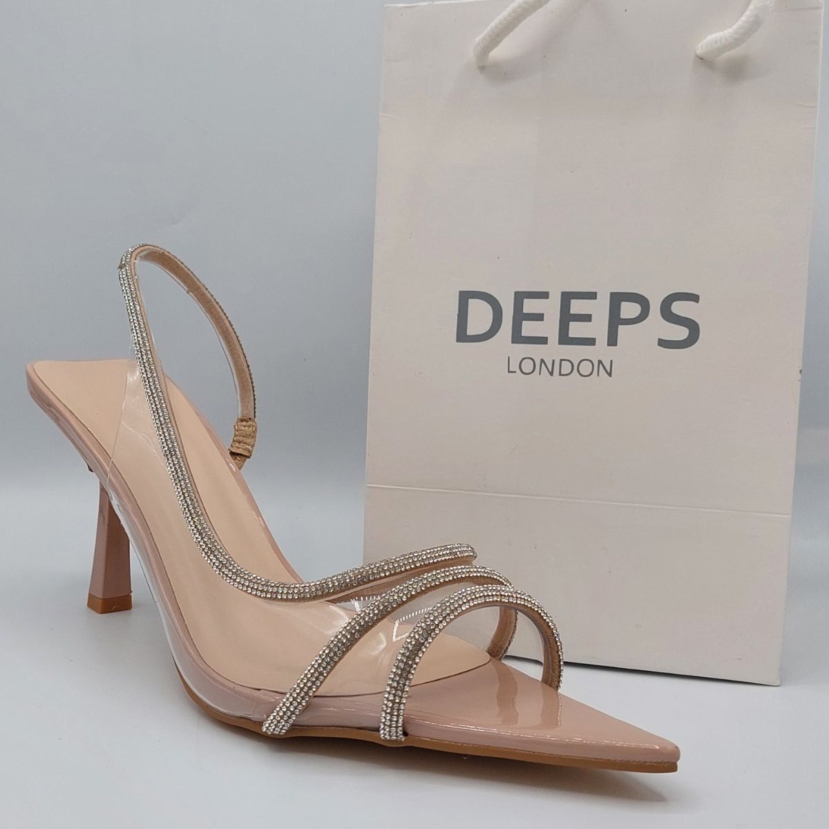 Front view of women's clear perspex slingback stiletto heels with shiny rhinestone embellishments, a glamorous choice for London occasions.