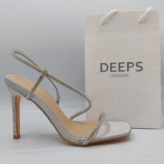 Side profile of women's strappy diamante stiletto heel sandals in silver, showcasing the stiletto heel and diamante strap detailing for London fashion.