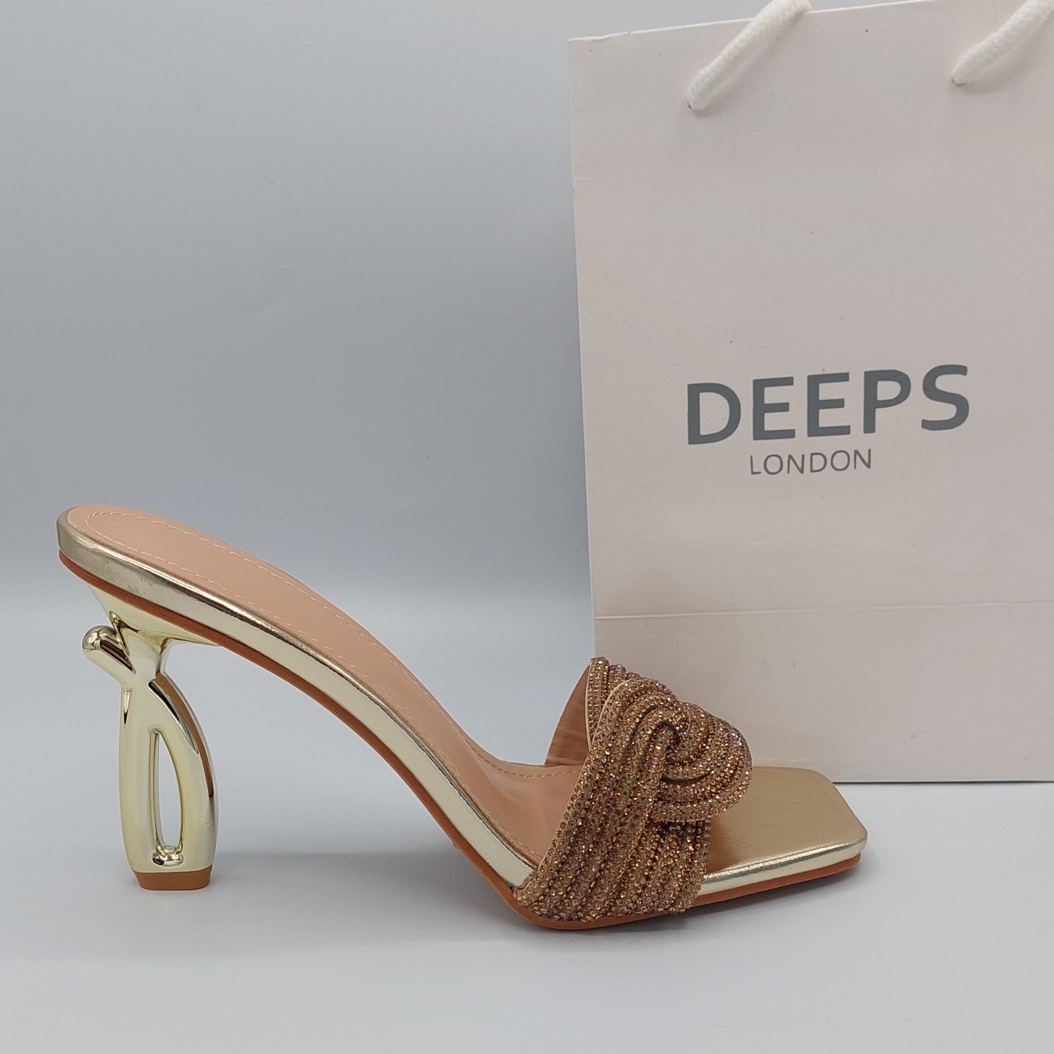 Front view of women's strappy embellished mule heel sandals in gold, a glamorous choice for London occasions.