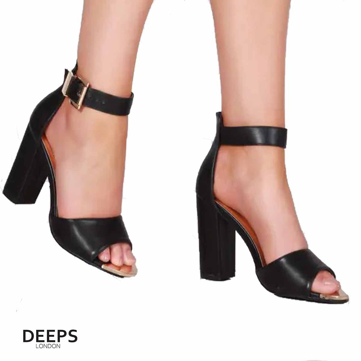 Woman's foot wearing stylish Belgravia chunky buckle strap block heel sandals (approx. 4-inch heel) in Black Suede, a fashionable and confident choice for London events from DeepsLondon.
