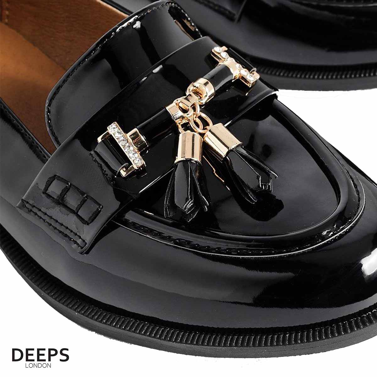 Close-up of the gold bar and tassel detailing on women's black classic slip-on loafers, highlighting their subtle and sophisticated accents in London.