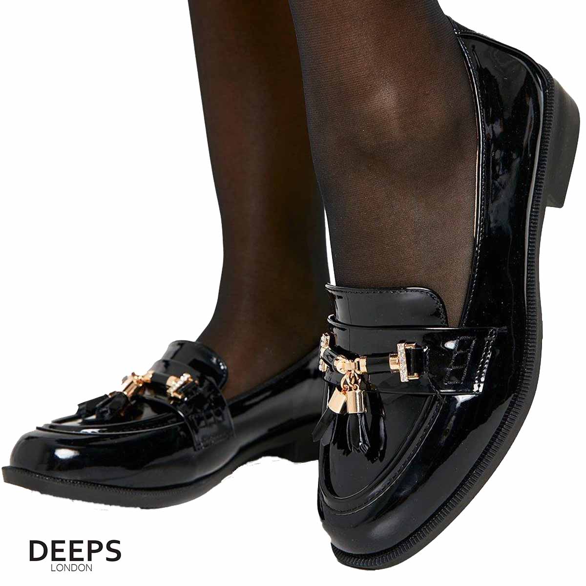 Side profile of women's black classic slip-on loafer with a gold bar and tassels, showcasing its elegant silhouette and refined design, perfect for London fashion.