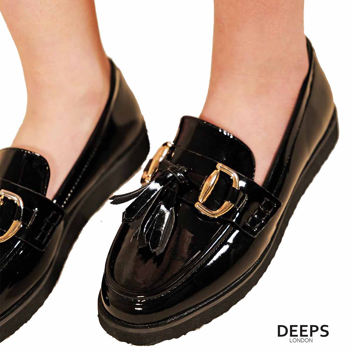 Close-up of the gold bar and tassel detailing on women's black patent classic slip-on loafers, highlighting their refined accents in London.