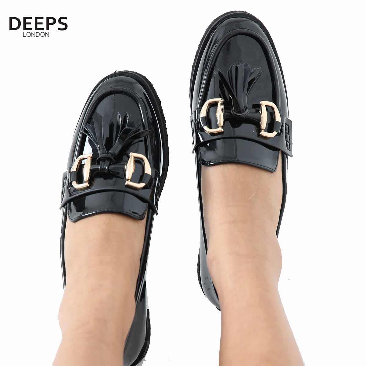 Front view of women's black patent classic slip-on loafer with a gold bar and tassel detail, a stylish and elegant shoe in London.