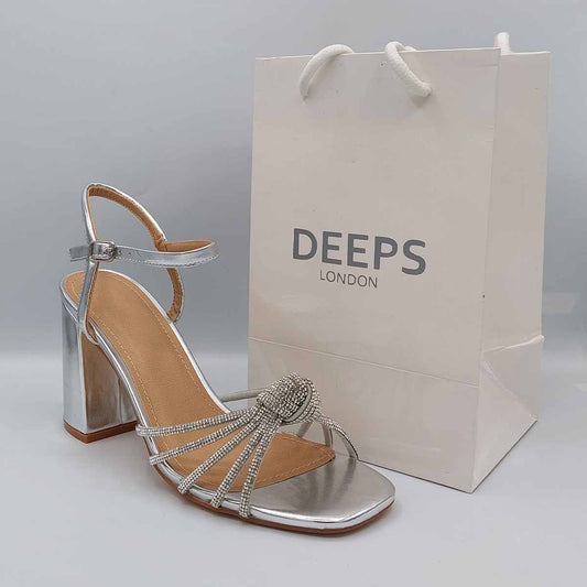 Front view of women's block heel buckle strap sandals with a butterfly knot front strap in silver, elegant London style from DeepsLondon.