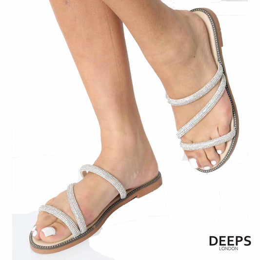 Front view of women's cross strap flat slider sandals in beige with sparkly embellishments, a glamorous choice for London.