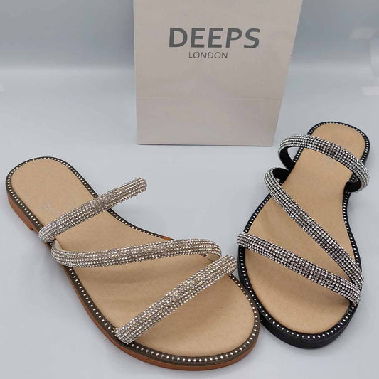 Front view of women's cross strap flat slider sandals in black and beige with sparkly embellishments, a glamorous choice for London.
