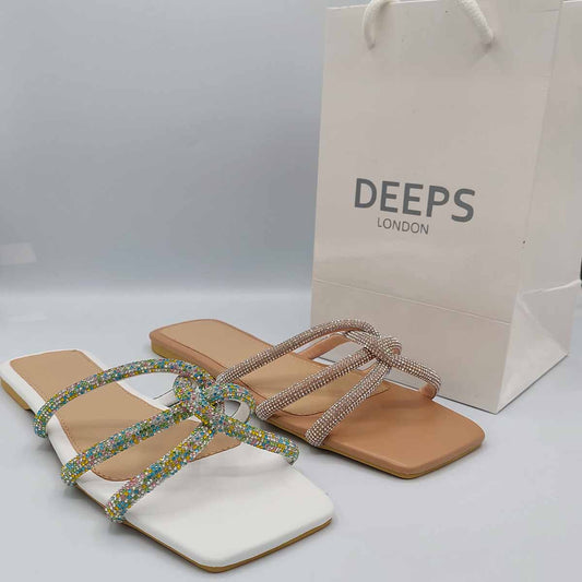 Front view of women's crystal cross strap flat slider sandals in beige and white with diamante embellishments, a glamorous choice for London.