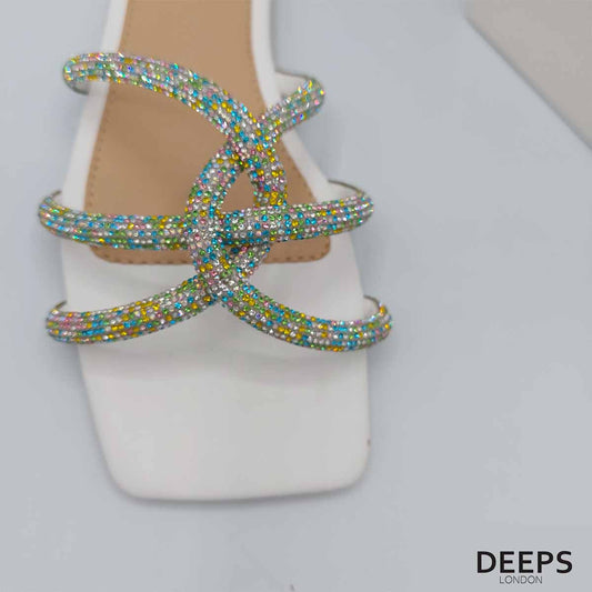 Close-up of the crystal stones and diamante embellishments on the cross straps of women's flat slider sandals in white, highlighting their glamorous features from DeepsLondon.