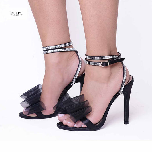Woman's foot wearing stylish Majesty organza bow high heel sandals in black satin, a fashionable and elegant choice for London events from DeepsLondon.