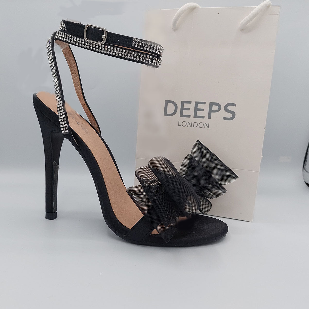 Side profile of Majesty organza bow high heel sandals in black satin, highlighting the stylish high heel and graceful design, London style from DeepsLondon.