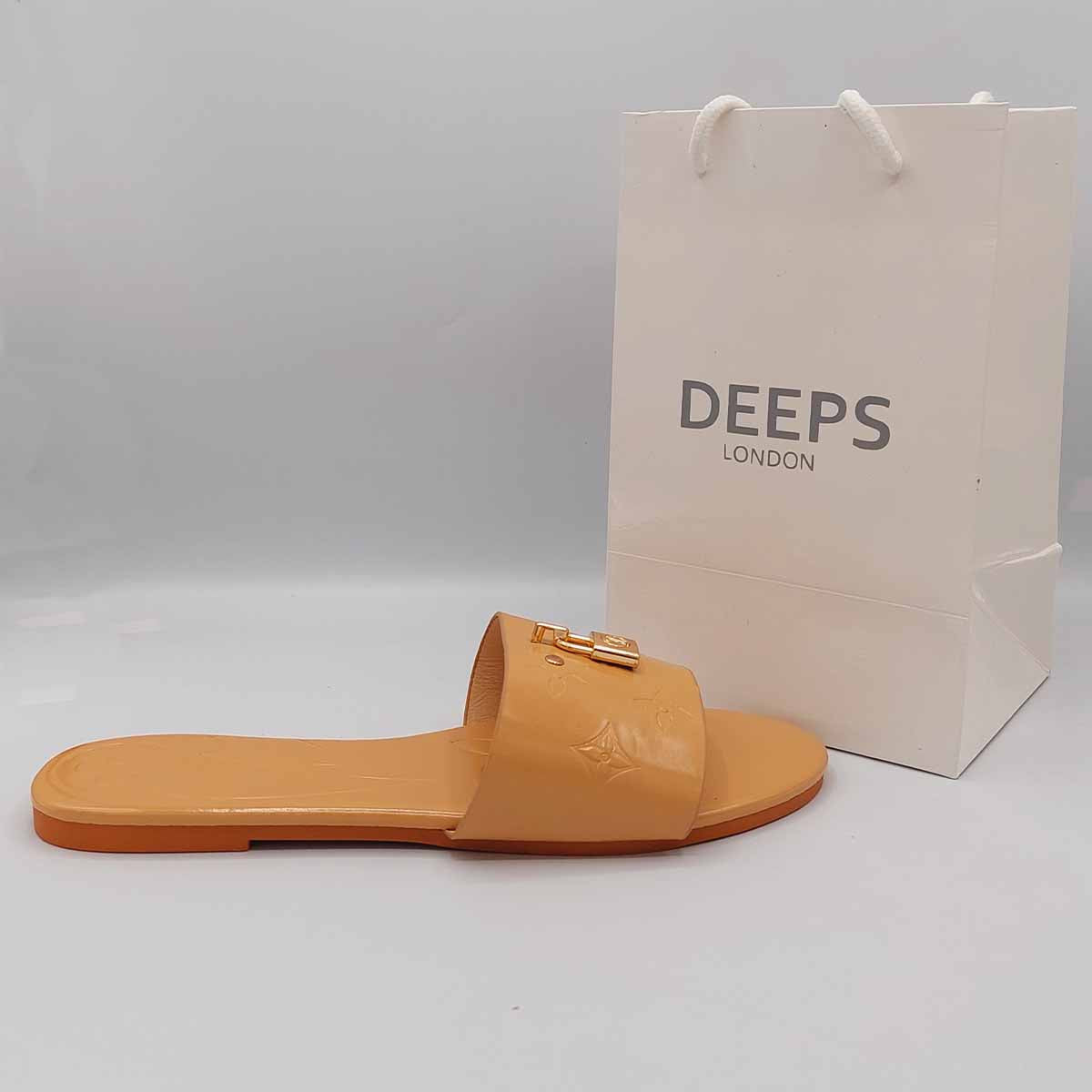 Front view of women's open toe flat slider sandals in beige with a gold lock detail, a chic and versatile option for London