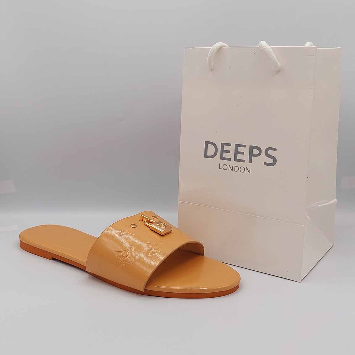 Side profile of women's open toe flat slider sandals in beige featuring a gold lock design on the strap, showcasing their easy slip-on style for London comfort.