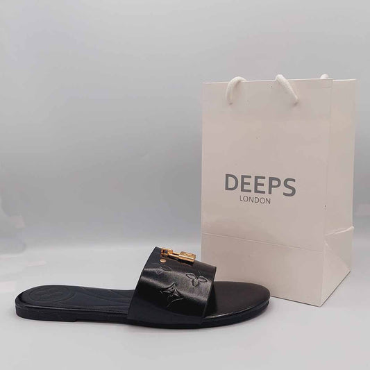 Side profile of women's open toe flat slider sandals in black featuring a gold lock design on the strap, showcasing their easy slip-on style for London comfort.
