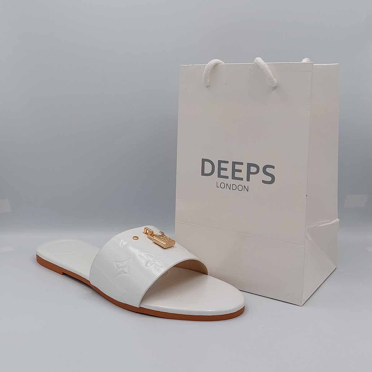 Woman's foot wearing stylish white open toe flat slider sandals with a gold lock detail, a comfortable and fashionable choice for London life from DeepsLondon.