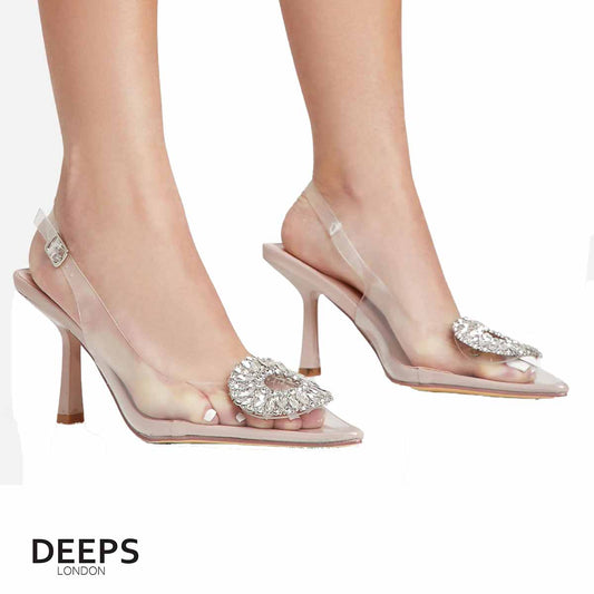 Woman's foot wearing stylish perspex court shoe with diamante brooch detail in nude, a comfortable and fashionable choice for London events.
